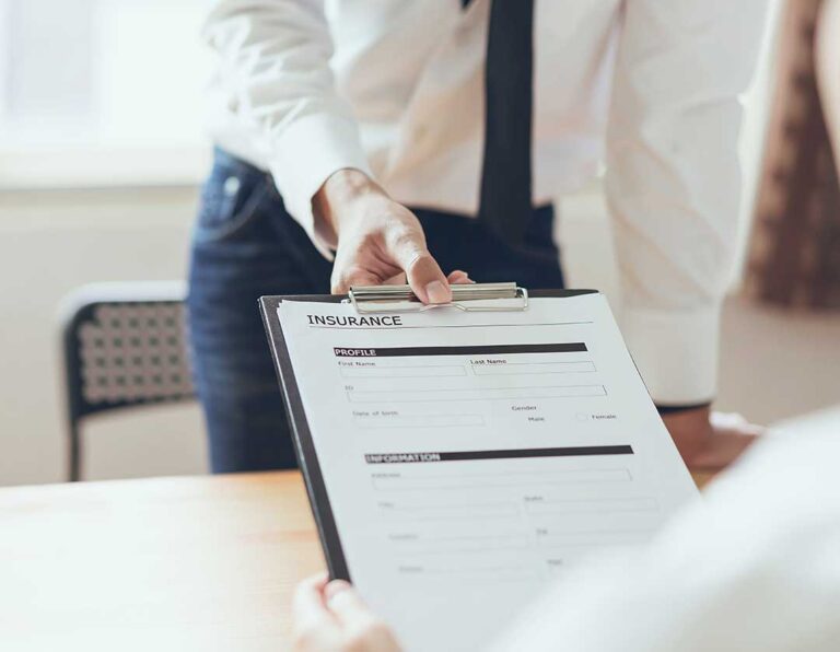 Person reviewing COBRA paperwork and health insurance documents at a kitchen table.